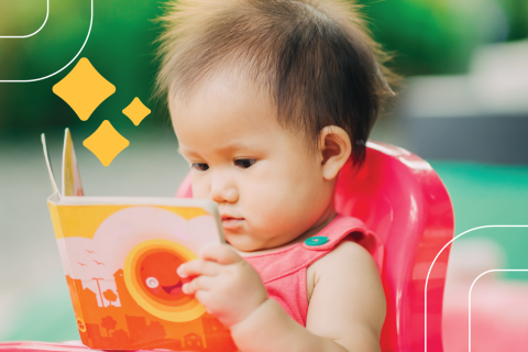 a baby in a high chair reads a board book