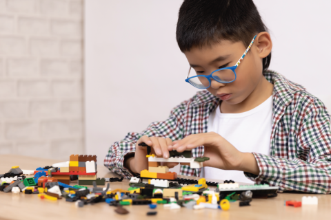 kid plays with legos at a table