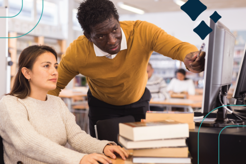 a library worker helps a patron at a computer