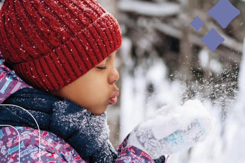 young girl blows snow our from her hands