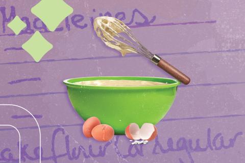 Whisk with batter floats over a mixing bowl next to cracked eggs on a background that shows the writing for a recipe