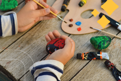kid paints a rock like a lady bug