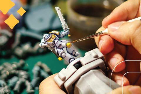man paints a miniature figure for a table top role playing game