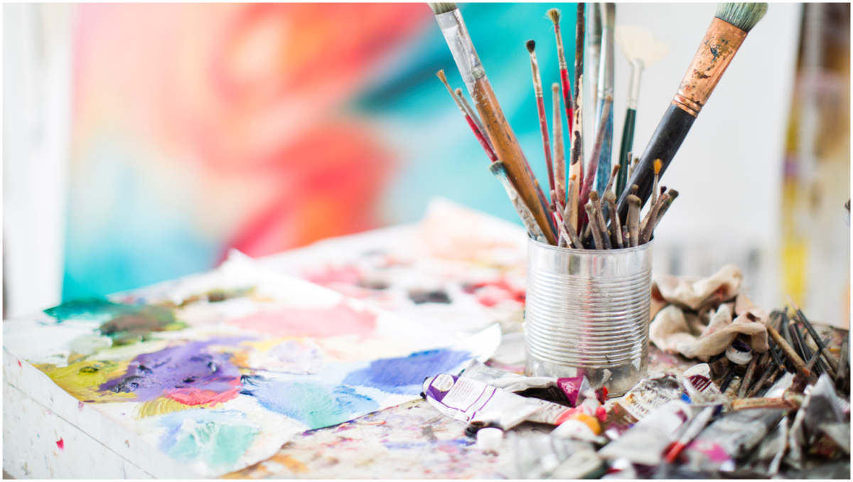 brushes in a coffee can and art supplies on a table
